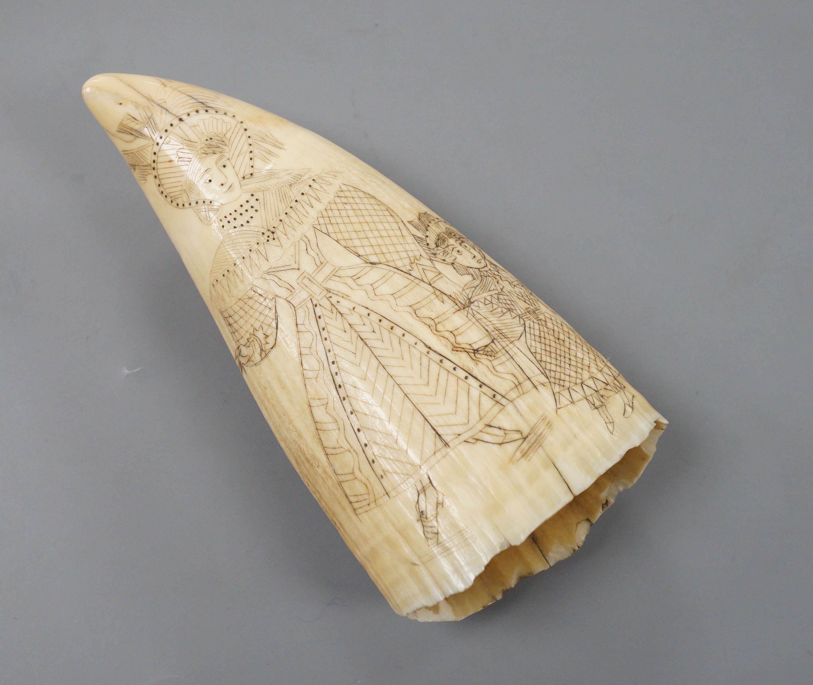A 19th century worked scrimshaw sperm whale tooth depicting a period mother and child, and British sailing ship to reverse, 14cm long
